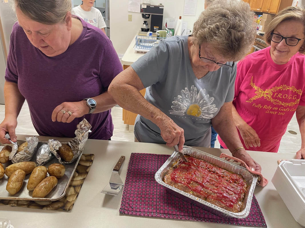 Cooks preparing potatoes and meatloaf