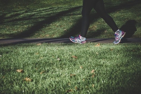 legs with sport shoes walking by green grass